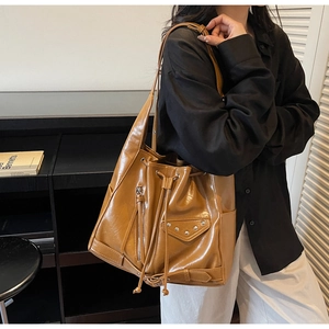 Brown faux leather bucket bag featuring moto-style zipper details and rivet pockets