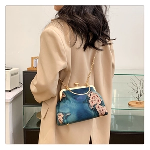 Detail of vintage navy blue floral kiss-lock bag with elegant gold chain strap and metal frame