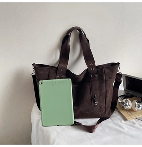 Macro view of a deep brown suede tote bag showing large capacity with a green tablet