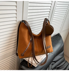 Detail view of large brown suede hobo bag with smooth leather trim and round coin pouch