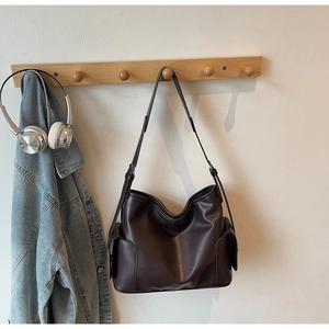 Detail showing deep brown faux leather tote with adjustable strap and side pockets