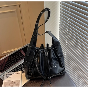 Detail of vintage black bucket bag showing glossy texture, rivets, and adjustable strap