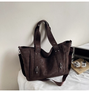 Detail view of brown canvas tote bag with metal rivets and adjustable shoulder strap