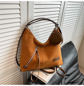 Detail view of brown faux suede tote bag with decorative zipper and small coin purse