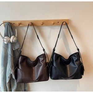 Detail of soft PU leather shoulder bags in brown and black with side flap pockets