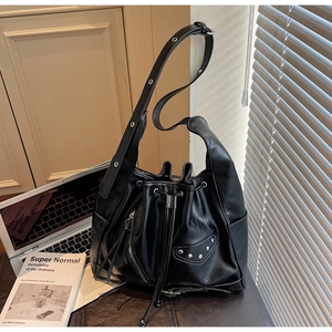 Close-up of black bucket bag with silver studs, tassels, and adjustable shoulder strap