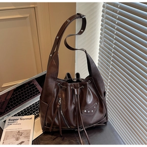 Detailed view of deep brown bucket bag featuring silver hardware and a side tassel zipper