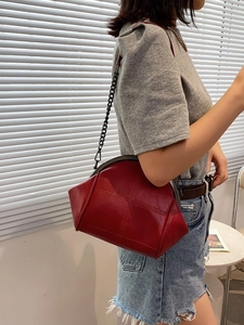 Classic red shell bag with metal chain strap shown on a model in bright setting