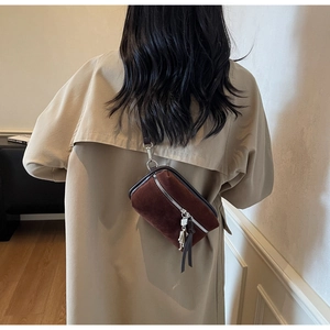 Detail view of dark brown suede mini bag with silver zipper and leather fringe tassels