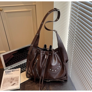 Detail view of vintage dark brown bucket bag featuring silver rivets and drawstrings