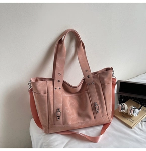 Detail view of pink tote bag with multiple pockets, metal ring, and nylon shoulder strap