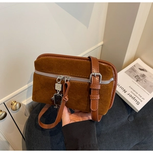 Detail of a brown suede crossbody bag featuring silver zipper and unique robot charm