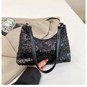 Detail of black sequined underarm bag showing glossy finish and leather shoulder strap