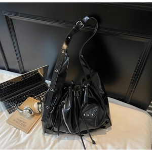 Black glossy biker style bucket bag with silver studs on a bed lifestyle scene