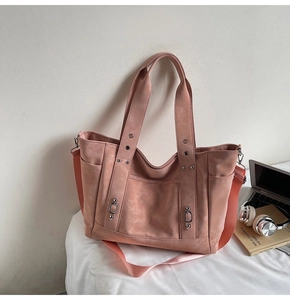 Detail of dusty pink tote bag showing front pockets and detachable woven shoulder strap