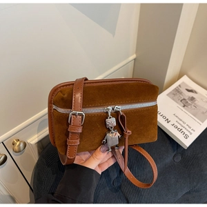 Detail of vintage brown suede crossbody bag with a cute silver robot pendant charm