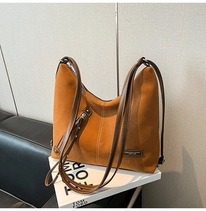 Detail of a brown suede tote bag with white contrast stitching and metallic zipper
