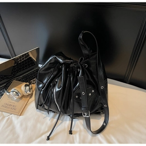 Detailed macro view of black shiny leather bucket bag with metallic rivets and side zippers