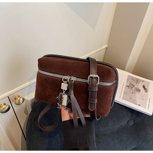 Detail of brown suede box bag with silver metal zipper and cute robot charm accessory