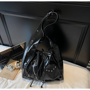 Detail of black oiled leather bucket bag featuring silver studs and drawstring closure