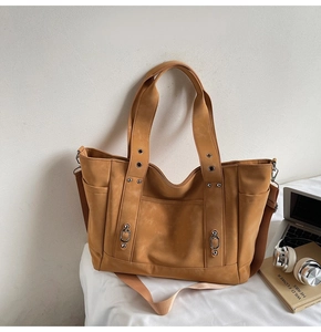 Close-up of vintage camel tote bag with matte texture, metal rings and side pockets