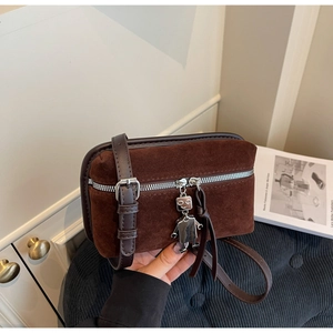 Detail of vintage brown suede crossbody bag with silver zippers and a cute robot charm