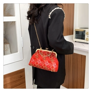 Detail view of red fan embroidery kiss-lock bag with gold handle on woman shoulder
