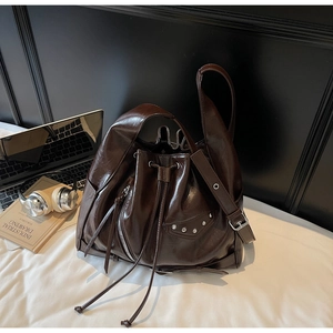 Detail view of brown bucket bag showing glossy PU leather and silver zipper accents