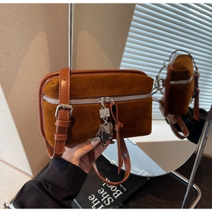 Detail of vintage brown suede crossbody bag with robot charm and adjustable strap