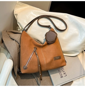 Detail of vintage brown suede tote bag with fringe zippers and adjustable shoulder strap