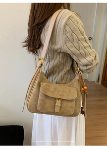 Model wearing a retro khaki frosted suede underarm bag with minimalist wood bead tassel