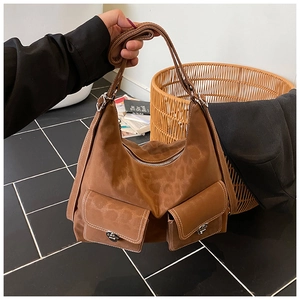 Detailed shot of large brown suede tote bag with front flap pockets and white stitching