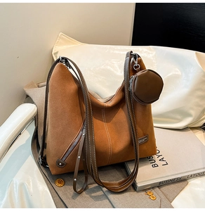 Detail of a large brown suede tote bag with contrast stitching and small round coin purse
