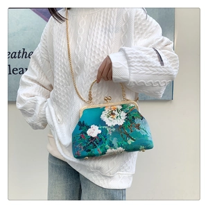 Detail of blue silk handbag featuring peonies and embossed gold metal frame and handle