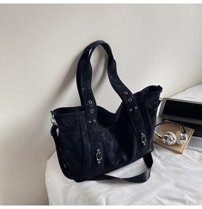 Detail view of black tote bag with silver eyelets and adjustable crossbody strap