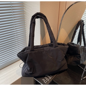 Close-up of black padded nylon tote with drawstring detail and glossy finish