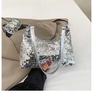 Close-up of silver sequined shoulder bag with metallic texture held against a beige blazer
