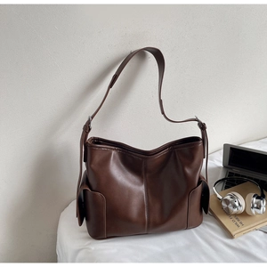 Detail view of the deep brown leather tote bag with side flap pockets and stitching