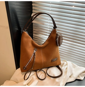 Close-up of caramel suede hobo bag with matching coin purse on white silk fabric background