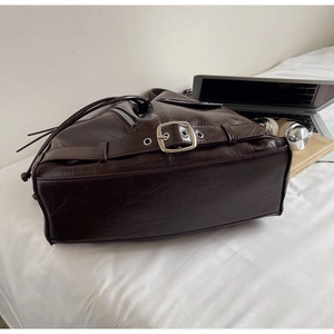Close-up of vintage large brown bucket bag with metallic buckle and drawstring closure