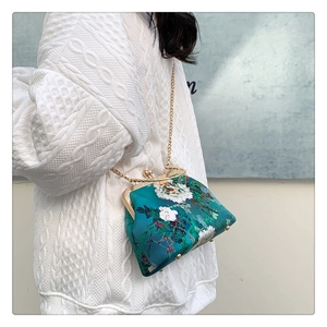 Detail of teal satin handbag with floral embroidery and golden metal clasp closure
