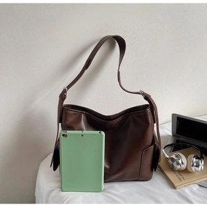 Detail of a large brown leather tote bag showing spacious capacity for a tablet device