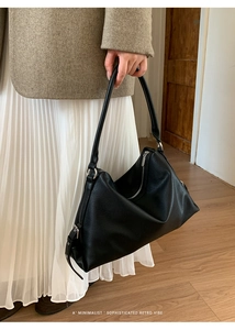 Detail view of black lychee grain leather texture and silver zipper on retro shoulder bag