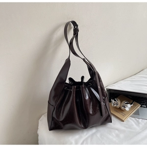 Macro detail of dark brown leather bucket bag with silver metal eyelets and drawstring closure