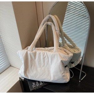Detail of off-white quilted puffer tote bag with side drawstring and wide padded handle