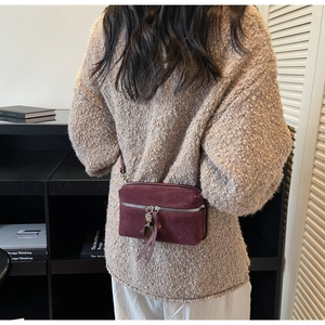 Detail of burgundy faux suede crossbody bag with silver robot charm and zipper