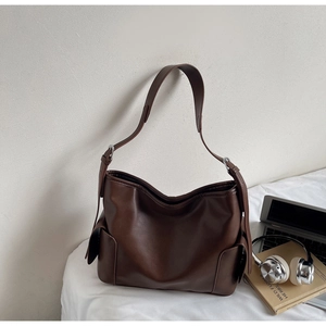 Macro shot of dark brown PU leather hobo bag with side flap pocket and silver buckle