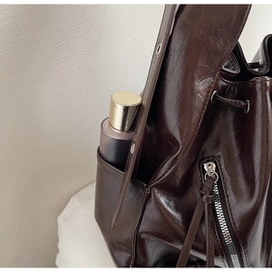 Detailed view of dark brown oil wax leather bucket bag featuring drawstring and side pocket