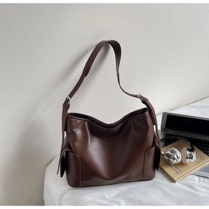 Detail of dark brown faux leather tote bag with functional side flap pocket and wide strap