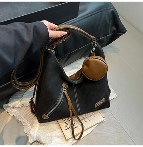 Detail of minimalist hobo bag with brown straps, rivet accents and small coin purse